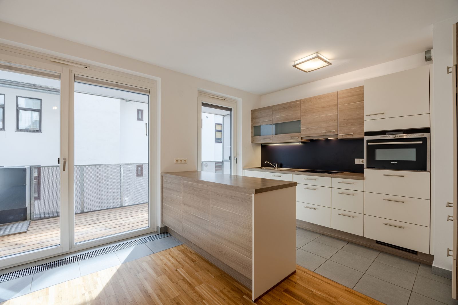 Wohnküche mit Kücheninsel und Fenstertüren zur Loggia